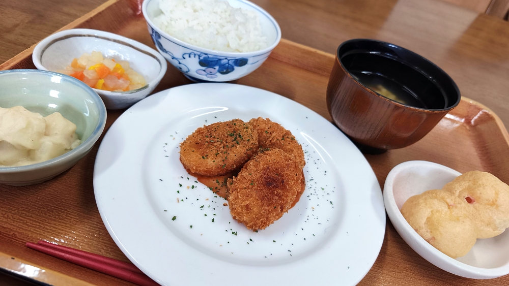 かにクロケット/ ベーコンポテト / 彩りピクルス / 汁物 / ご飯 / いちごプチシュー画像